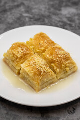 Baklava with milk (sutlu nuriye). Baklava with hazelnut and milk on a dark background.