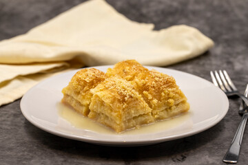 Baklava with milk (sutlu nuriye). Baklava with hazelnut and milk on a dark background.