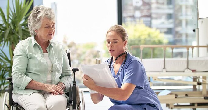 Keeping her patients spirits high. Caring nurse talking to old lady patient in a wheelchair at home or hospital. Doctor helping a mature senior woman read paperwork with an elderly healthcare concept