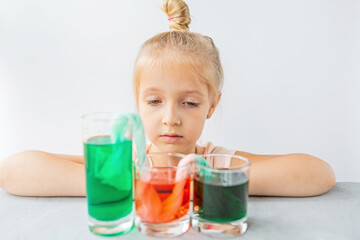 cute little girl six years old doing laboratory experiment with colorful water in classroom. Education science concept. Selective focus. Distance learning during covid-19 coronavirus quarantine.