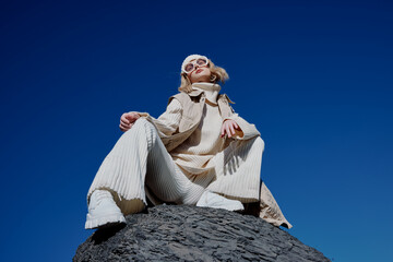 Fototapeta premium young woman sitting on a stone nature blue sky in a hat lifestyle