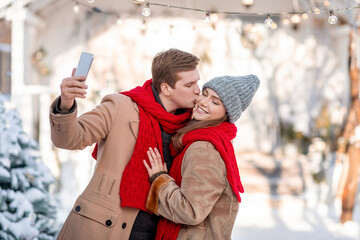 Romantic couple enjoying beautiful winter day, taking selfie - obrazy, fototapety, plakaty