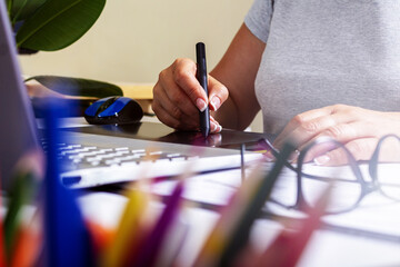 Woman working on graphics tablet with stylus. 