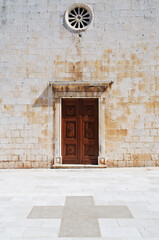 Entrance to roman catholic church on Brac island in Dalmatia, Croatia, with cross on the stone paved forecourt © Robert