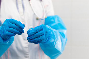 Doctor's hands in rubber medical gloves hold an ampoule of medicine in a hospital during the...