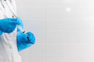 Doctor's hands in rubber medical gloves hold a syringe and an ampoule with medicine in a hospital...