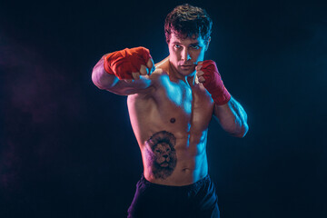Portrait of muscular kickbox or muay thai fighter who punching on black background. Sport concept.