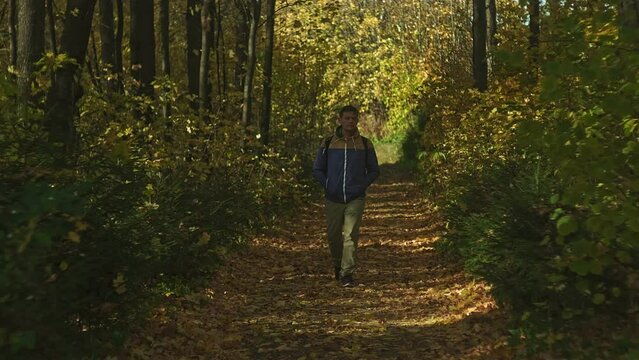 A mature man tourist traveler with a backpack walks in the autumn forest near the river