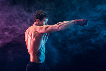Side view of aggressive boxer who training and practicing jab on smoke background. Sport concept - obrazy, fototapety, plakaty