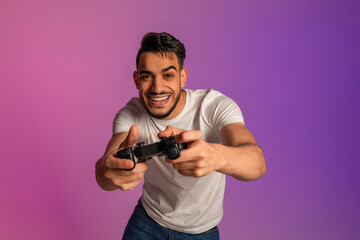 Handsome young Arab man using joystick, playing online video game in neon light © Prostock-studio