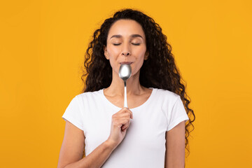 Portrait of Smiling Latin Lady Holding Spoon In Mouth - obrazy, fototapety, plakaty