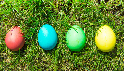 Four painted and decorative Easter eggs in the grass. Top view, copy space