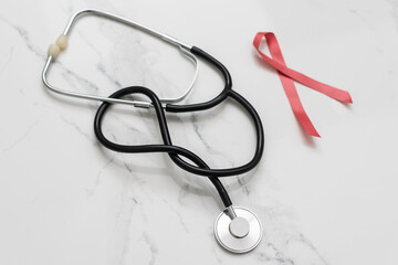 red ribbon with a cancer day phonendoscope. women's and men's health