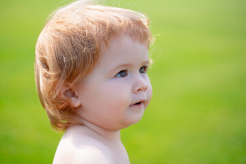 Cute little baby on the meadow field. Toddler child walking outdoor, family vacations, summer season nature. Baby face close up. Funny little child closeup portrait. Blonde kid, emotion face.