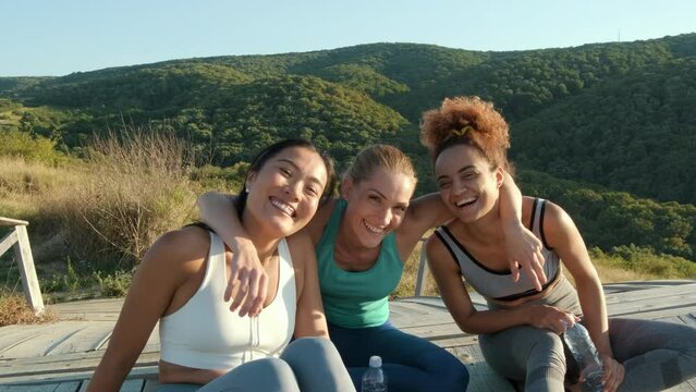Group of sporty female friends resting after running outdoors.