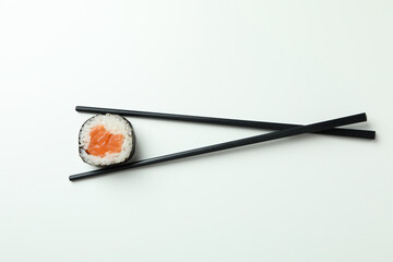 Chopsticks with maki on white background, top view