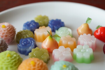 Thai dessert flower shape is Layer Sweet (Kanom Chan) & dessert stuff with crushed soybean and taro(Chor Phaka Krong), A fruit shape is Deletable Imitation Fruits. (Look Choup)