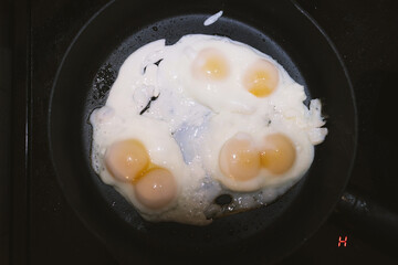 Three scrambled eggs with six yolks. One egg with two yolks in a black frying pan.