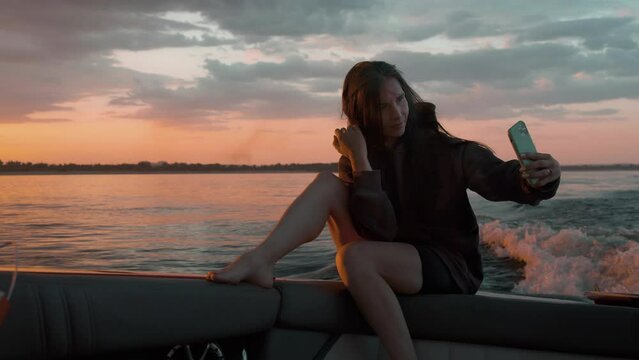 A woman takes a picture of herself at sunset in a motor boat
