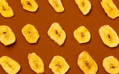 Yellow banana chips on a brown background.
