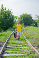 happy tourist with a suitcase walking on the railroad
