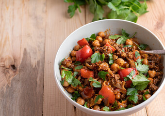 Ground beef with chick peas and vegetables in a bowl isolated on wooden table from above