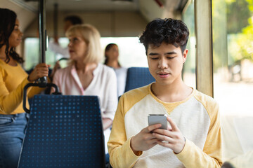 Portrait of Asian guy using cellphone in bus