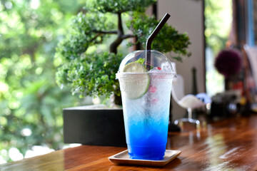 Closeup glass of blue lagoon cocktail decorated with lime at bar counter beverage shop background. Cold drinks and cocktails in summer. selected focus - obrazy, fototapety, plakaty