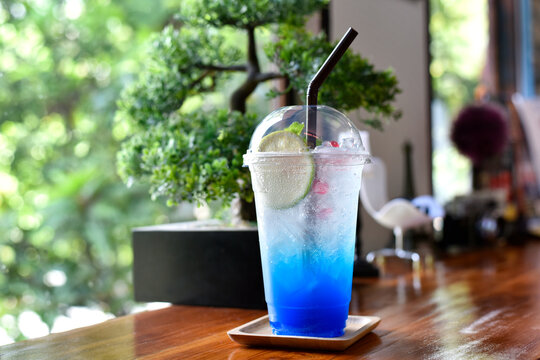 Closeup glass of blue lagoon cocktail decorated with lime at bar counter beverage shop background. Cold drinks and cocktails in summer. selected focus