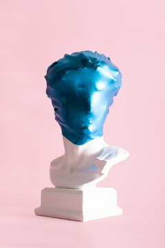 Plaster Male Head Wrapped In Shinny Blue Stretch Fabric Against Pastel Pink Background. Blue In The Face Idea, Creative Layout. 