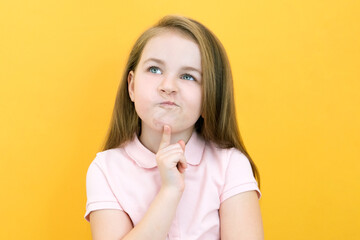 Fototapeta premium Thoughtful little girl touching observation chin, thoughtful cute daughter making decision, imagining thought, posing isolated over yellow