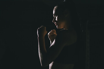 Young woman boxer in the dark in contour light. Side view