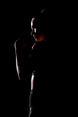A silhouette of a woman standing in a fighting stance. Dark dramatic scene performed in a low key.