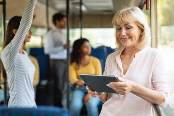 Portrait of smiling senior woman taking bus using tablet © Prostock-studio