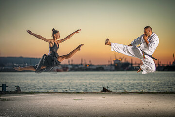 Karate fighter and girl gymnast practising kick in the air at sunset