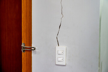 Close up photo of cracked wall texture near the light switch