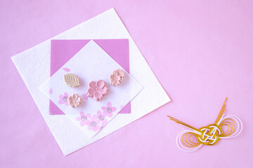 桜模様の和紙の上の桜の干菓子と金と白の水引