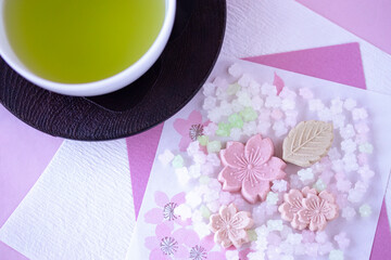 緑茶と和紙の上の桜の干菓子と金平糖のクローズアップ