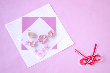 桜模様の和紙の上の桜の干菓子と紅白水引
