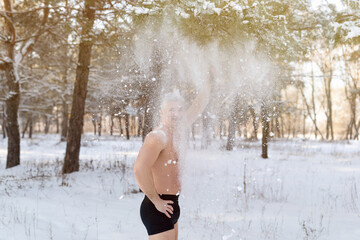 Happy mature man in underwear throwing snow at himself in winter park. Cold weather training and winter fun concept