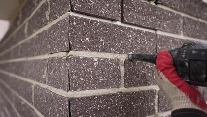 Applying grout to the joints between tiles. The seam is filled with the prepared mixture using a gun. A trowel gun at work. Seams between tiles are filled with a syringe gun.