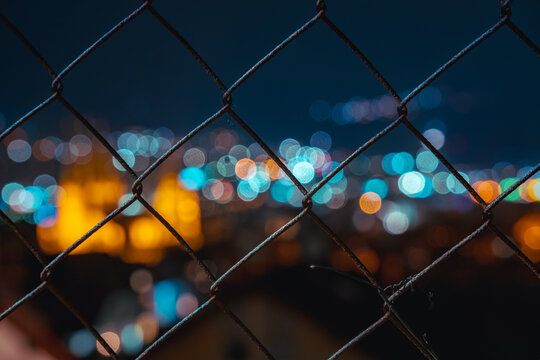 Buntes Bokeh der Stadt Gelnhausen hinter Maschendrahtzaun 