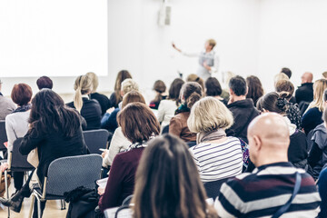 Female speaker giving a talk at business meeting. Audience in conference hall. Business and...