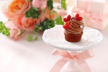 Chocolate cupcake with chocolate cream with strawberry heart. 
Valentine bouquet of rose flowers ...