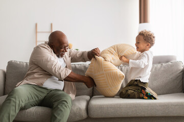 Black Grandpa And Little Grandson Having Pillow Fight At Home