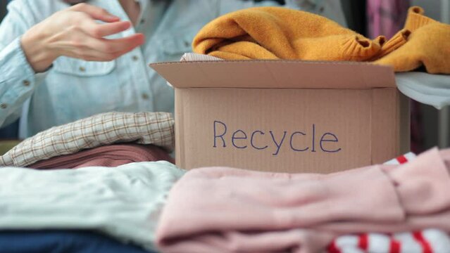 a woman collects clothes in a box for recycling or disposal.european woman sorting plastic and garbage eco friendly lifestyle and caring for the planet. disassemble the wardrobe at home for donation