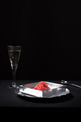 Caviar de salmón rojo con copa de vino blanco  sobre fondo negro. Aperitivo, comida delicatessen de lujo	