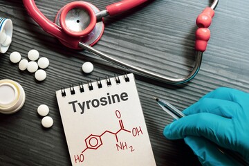 Notepad with the text and chemical structure of L Tyrosine on table with pills stethoscope. This...