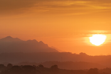 BEAUTIFUL ORANGE SUNSET WITH MEADOWS AND MOUNTAINS IN THE BACKGROUND