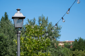Fototapeta na wymiar Illumination landscape light park with electric garland of light bulbs